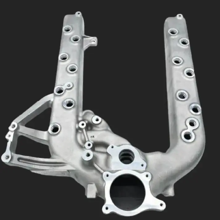 Silver metal engine intake manifold with multiple mounting points.